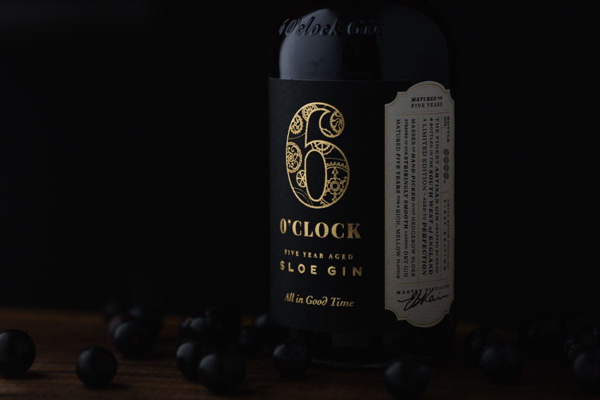 Bottle of sloe gin surrounded by sloe berries
